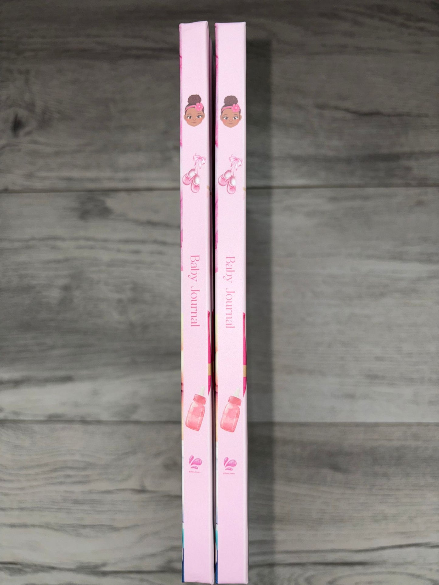 Two pink books with illustrations on a wooden surface