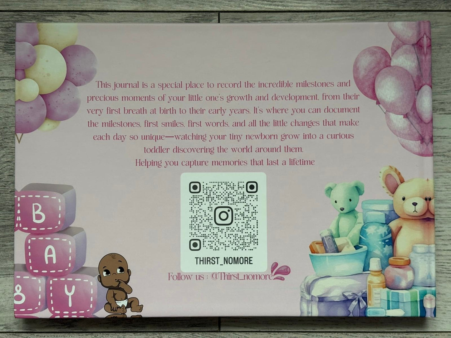 Product packaging for a baby journal with toys and text on a wooden surface