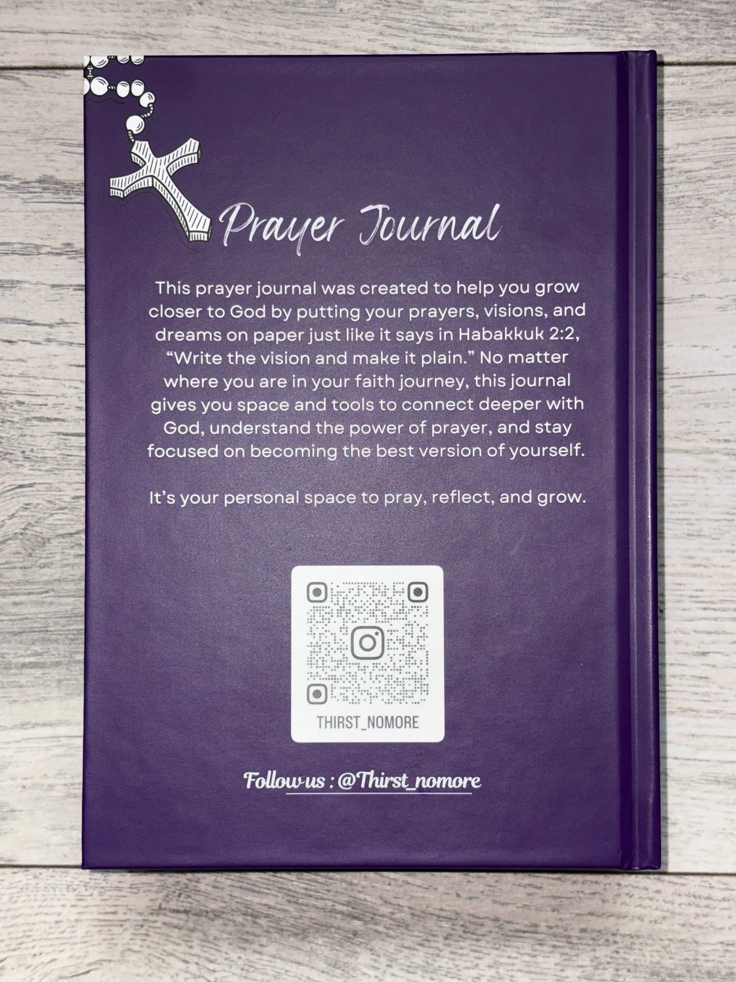 Purple prayer journal with text and QR code on a wooden surface